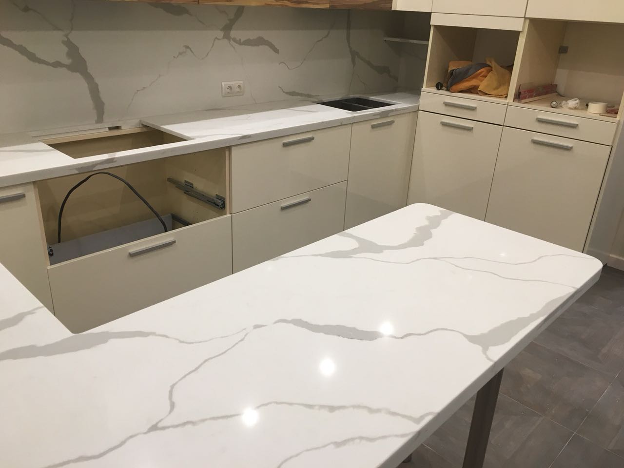 Столешница из кварца с барной стойкой и подоконником. Цвет кварца калаката: белый мрамор с темными (черными) полосами.