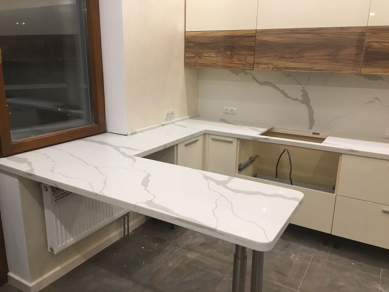 Вид на ту же столешницу с другой стороны. Барная стойка из кварца калакатта опирается на 2 хромированные металические ноги.